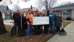 Group of IVS volunteers pose in a front yard with their rakes and a big donation check to IVC.